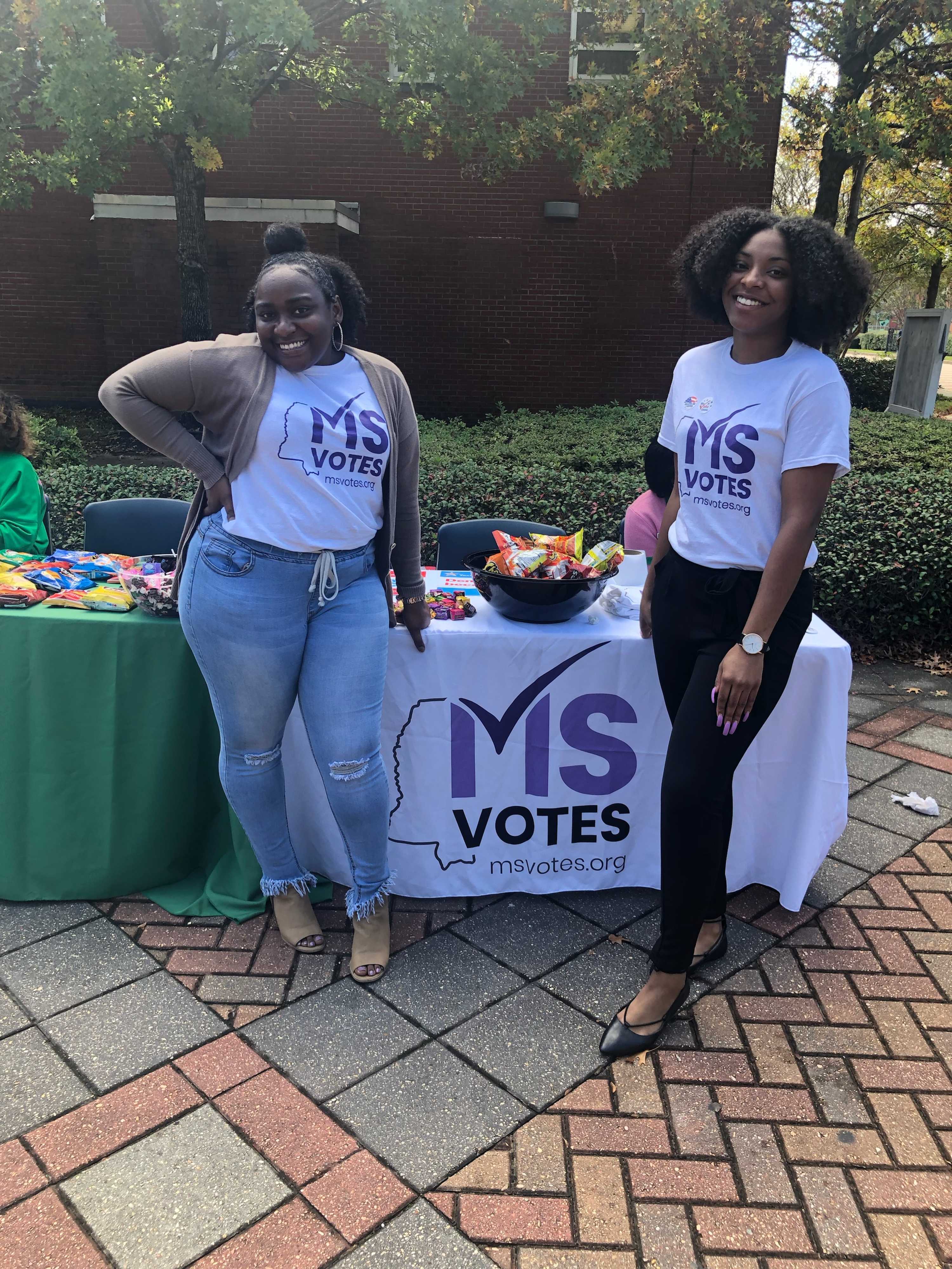 Two women at a college campus ready to tell folks about MS Votes.